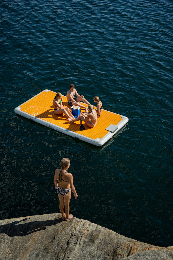 Sommerspaß auf einem aufblasbaren Floß, vier Freunde die auf dem See relaxen