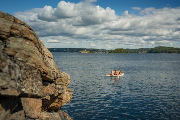 Sommerspaß auf einem aufblasbaren Floß, vier Freunde die auf dem See relaxen